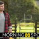 Tom Welling as Clark Kent in the CW's Crisis on Infinite Earths Crossover wears a red flannel shirt over a grey shirt and stands on a farm..